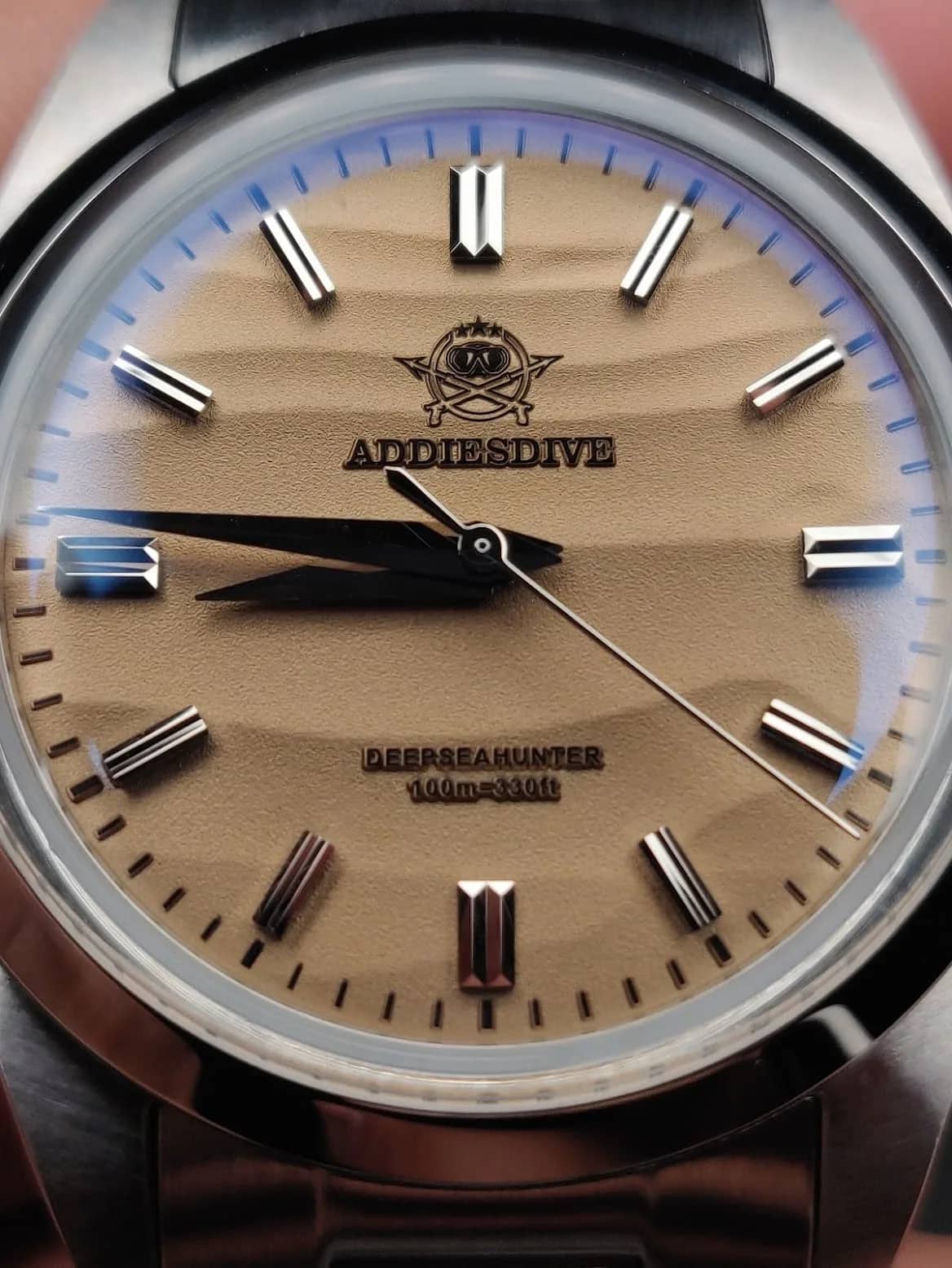 Macro frontal del AD2030 con brazalete de acero: la textura de arena de la esfera y las agujas dauphine negras en detalle