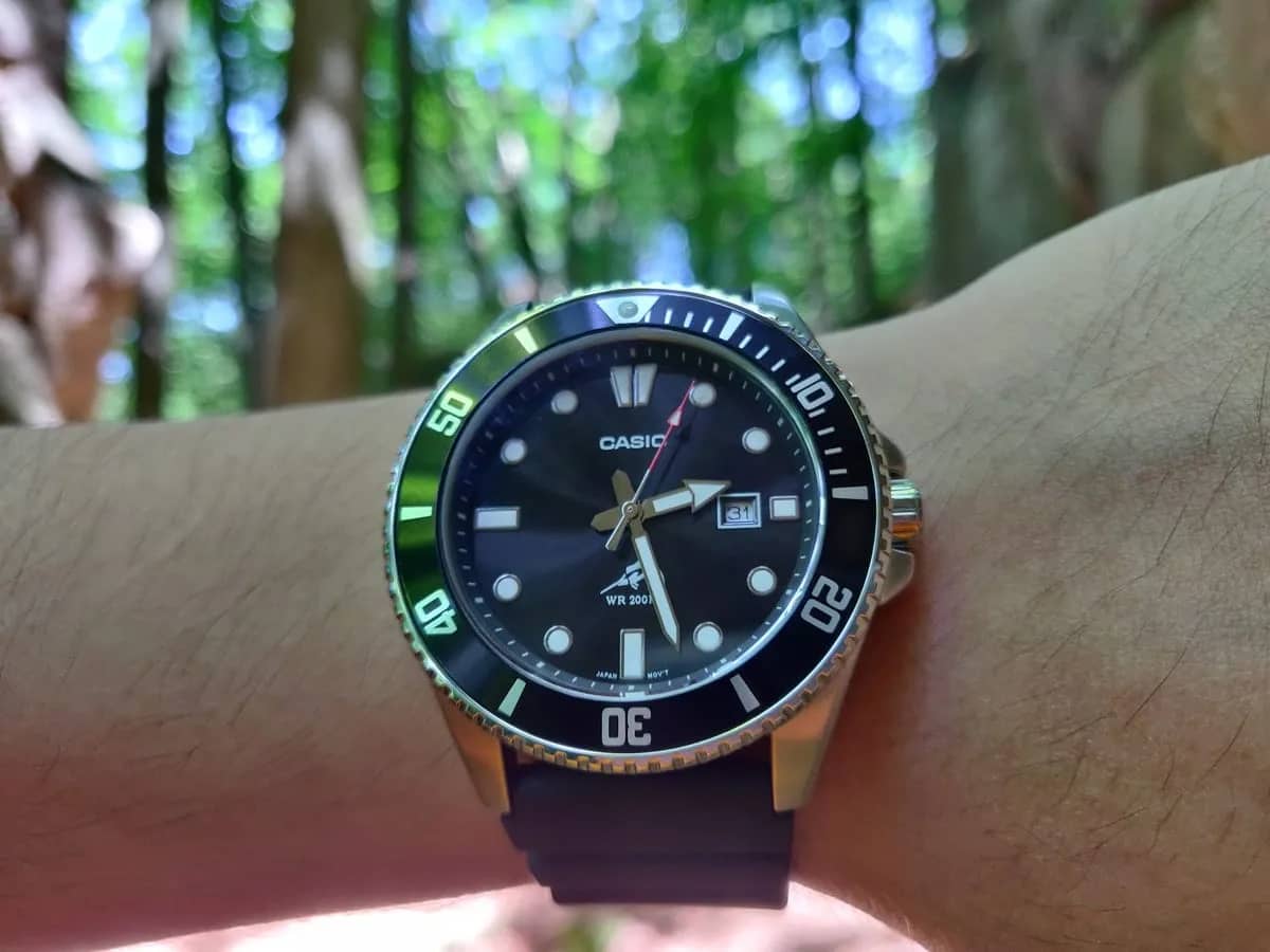 Wrist shot en el bosque: el bisel negro con reflejos verdes y el marlin sobre «WR 200M» en la esfera