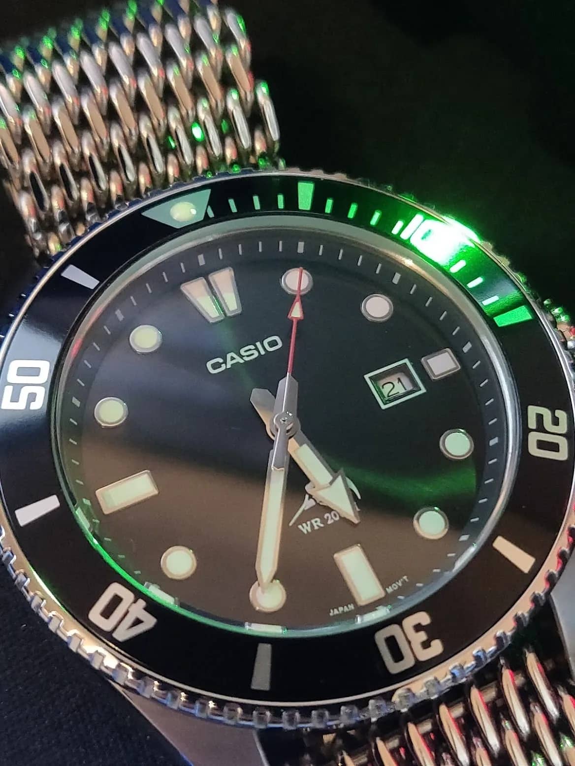 Macro con reflejos verdes sobre la malla de acero: el lumen de los índices y la fecha a las 3