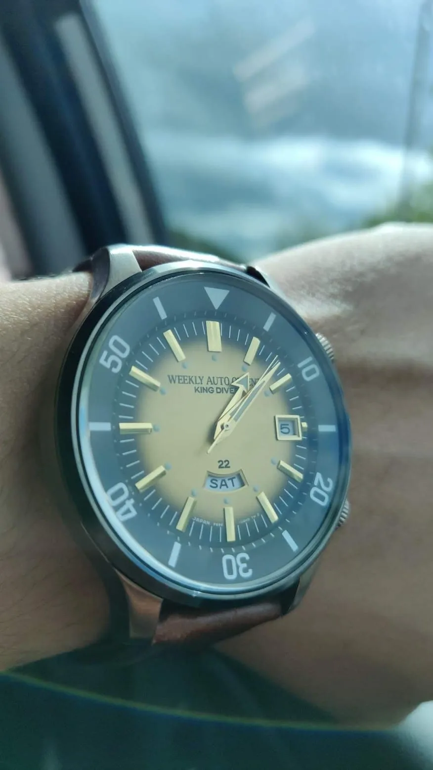 Wrist shot en el coche: el degradado dorado de la esfera iluminado por la luz de la ventanilla