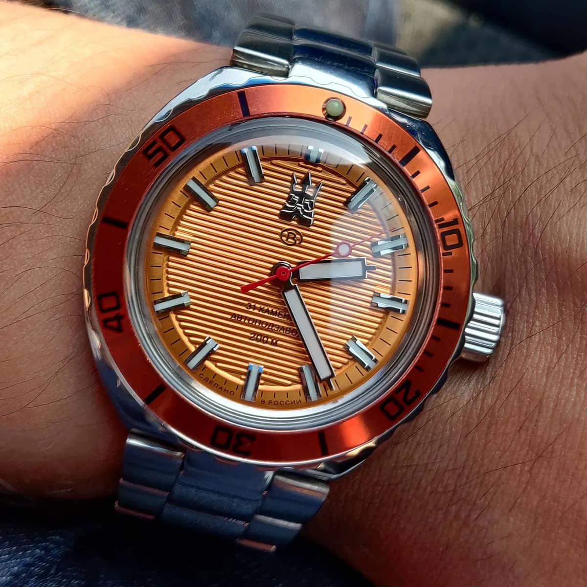 El Amphibia Neptune al sol en la muñeca: el segundero rojo y los índices dobles brillando sobre el naranja