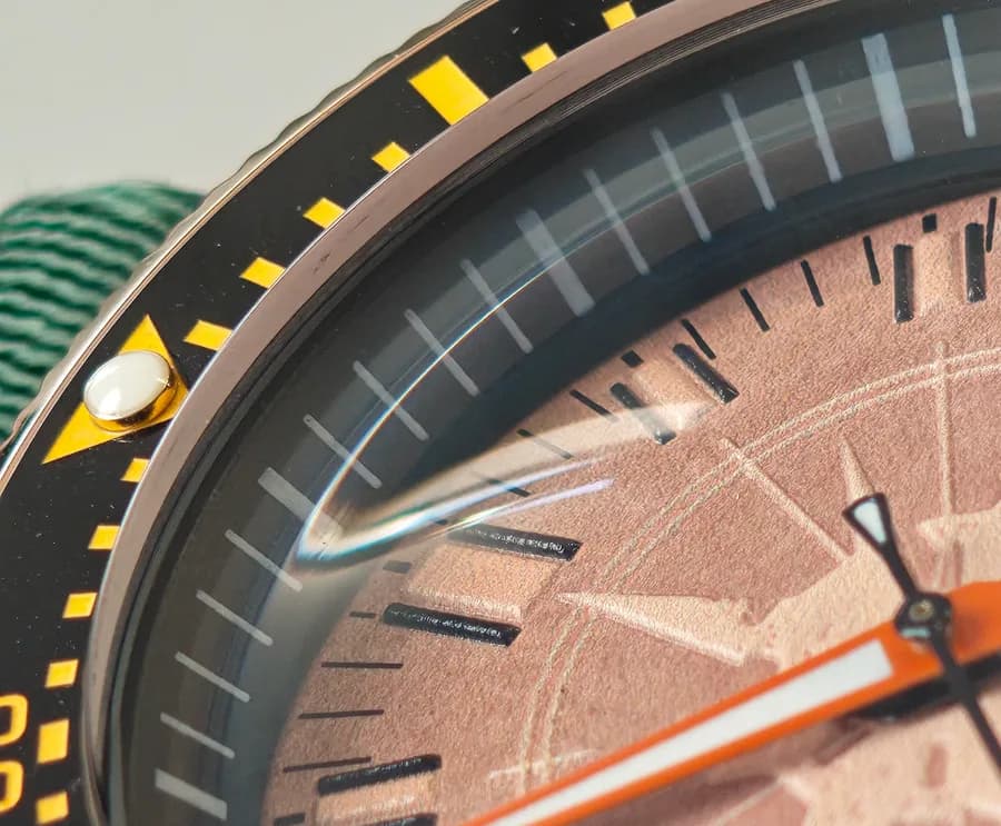Macro del inserto cerámico negro montado en el reloj, con el punto luminoso a las 12 y la escala amarilla