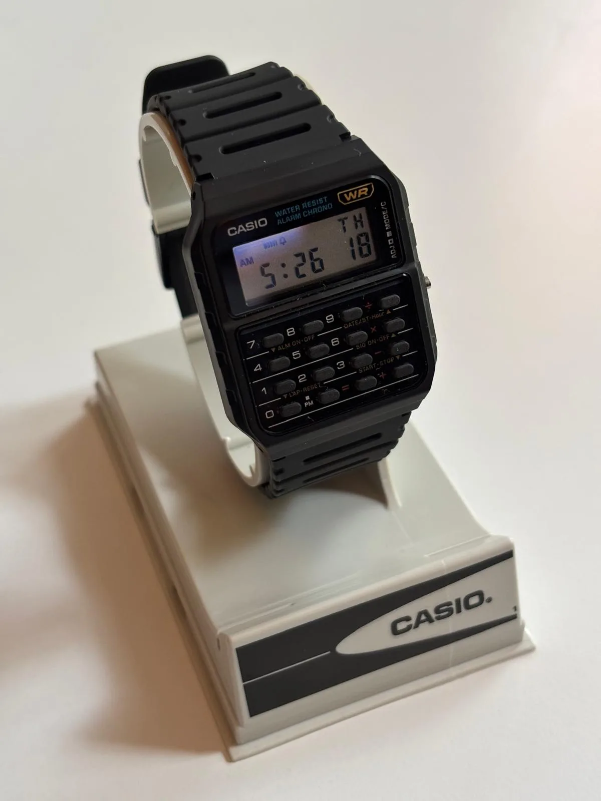Casio CA-53W-1ER de tres cuartos sobre su soporte, reloj calculadora de resina negra con teclado de ocho dígitos y pantalla LCD, propiedad de Till S.
