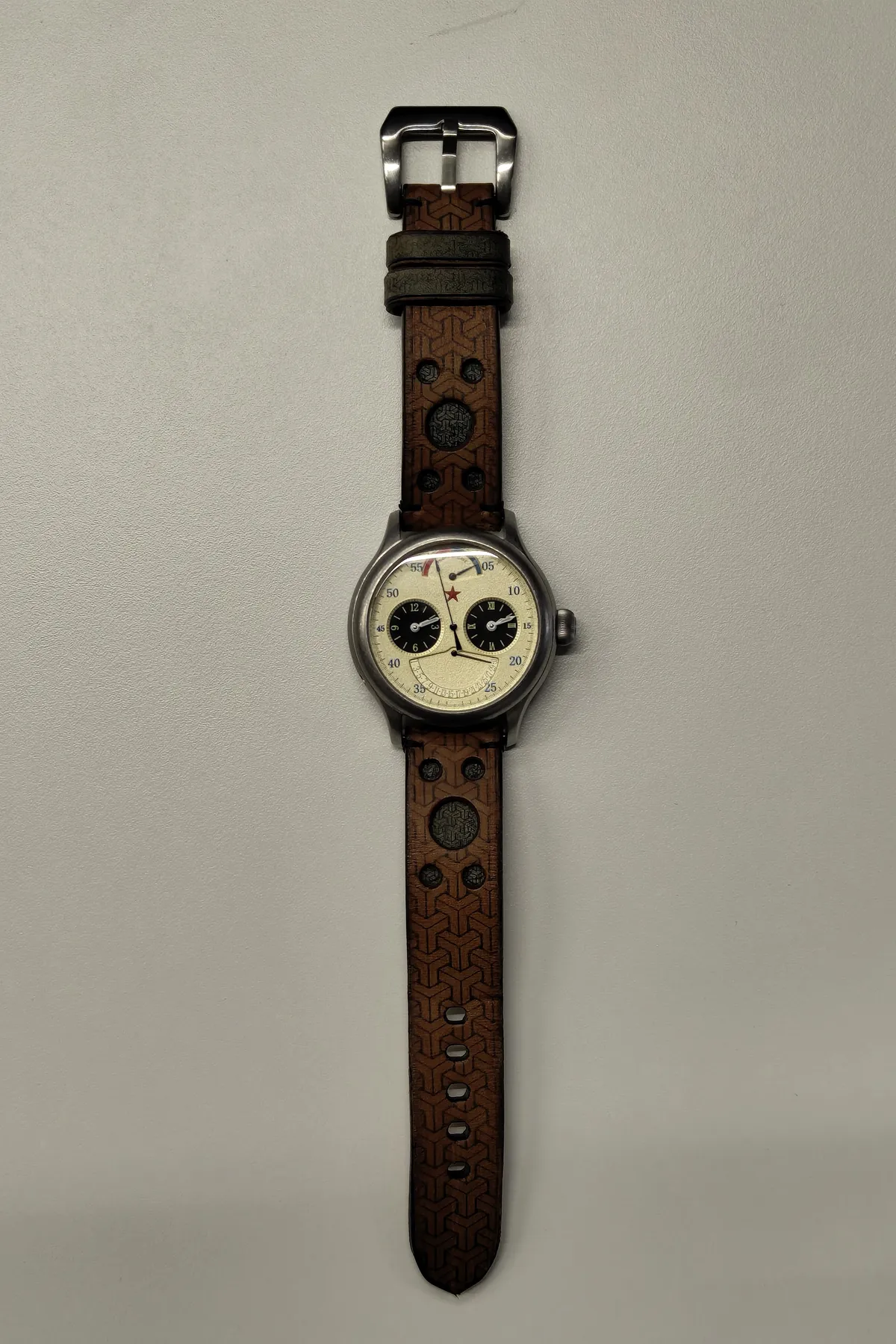 El reloj completo sobre su correa de cuero personalizada estilo rally, con grabado geométrico y perforaciones